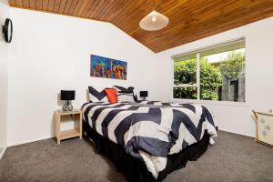a bedroom with a black and white bed and a window at Pats Place on the Beach in Papamoa