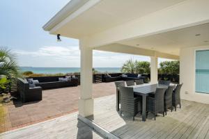 een patio met een tafel en stoelen en de oceaan bij Pats Place on the Beach in Papamoa