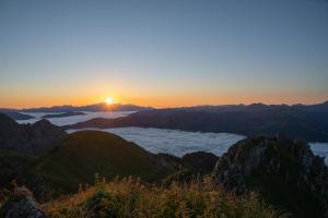 a sunset on the top of a mountain with clouds at Hotel Gratz Großarl in Grossarl