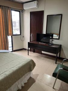 a bedroom with a bed and a desk with a television at Hotel Rizzo in Guayaquil