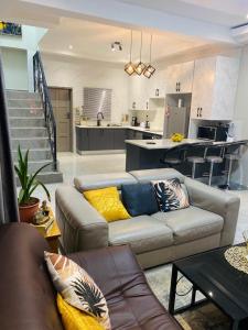 a living room with a couch and a kitchen at modern, two-story luxury house in Gaborone