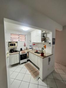a kitchen with white cabinets and a white tile floor at Nosso apê no Guarujá - Unidade Aquário in Guarujá
