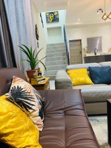 a living room with a couch and yellow pillows at modern, two-story luxury house in Gaborone