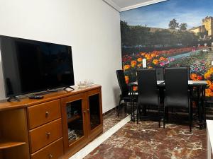 un salon avec une télévision et une table avec des chaises dans l'établissement GRACIA, à Cordoue