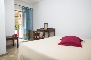 una camera da letto con un letto bianco con un cuscino rosso di Il Gelso Vacanze a Malfa
