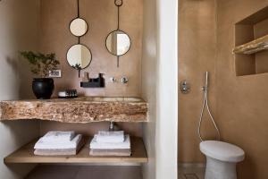 uma casa de banho com um lavatório, um WC e espelhos em Apsila Pool Suites em Sifnos