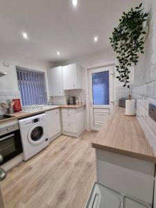 a kitchen with white cabinets and a washing machine at Cosy modern house in Liverpool