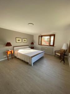 Spazio Friuli - Tiare Apt. residenza nel verde في Sevegliano: غرفة نوم كبيرة مع سرير كبير وكرسي