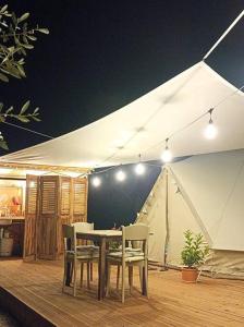 een tafel en stoelen op een terras met een tent bij Meltheane in Lygia