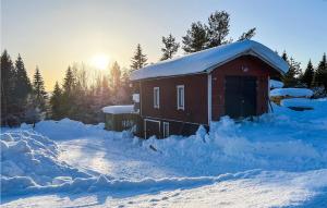 a snow covered cabin with the sun in the background at Amazing Home In Frnsta With Sauna, Wifi And 3 Bedrooms in Fränsta