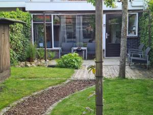 een tuin met een huis met een houten paal bij Bed & Breakfast 28 appartement met ruime tuin en gratis prive parkeren ideaal voor gezinnen in Assen