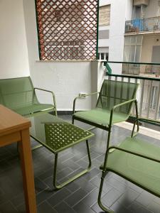 two green chairs and a table on a balcony at Case vacanze Monroe 1 in Palermo