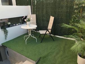 una mesa y una silla en un parche de hierba en Precioso Apartamento nuevo con Jardín privado, en Paracuellos de Jarama