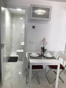uma sala de jantar branca com uma mesa e uma casa de banho em Precioso Apartamento nuevo con Jardín privado em Paracuellos de Jarama