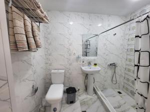 a white bathroom with a toilet and a sink at Bobo Haydar Guest House in Bukhara
