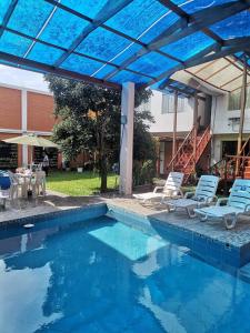 una piscina con sillas y una sombrilla azul en La Casa del Abuelo ESPECIALIZADO PARA FAMILIAS, en Huaral