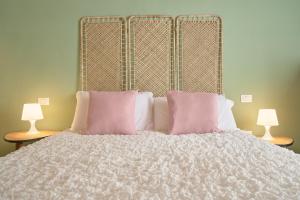 1 cama con 2 almohadas rosas y 2 lámparas en Green Coast House 4, en Piombino 3 fotos más