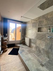 a bathroom with a shower with a stone wall at Spa privatif face mer Riva Romantic & SPA in Ouistreham
