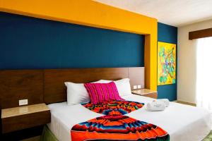 two beds in a room with a blue and yellow wall at Hotel Mariachi by Kavia 5th Av in Playa del Carmen