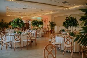 un salón de banquetes con mesas blancas, sillas y plantas en Parador Nature Resort and Spa, en Manuel Antonio