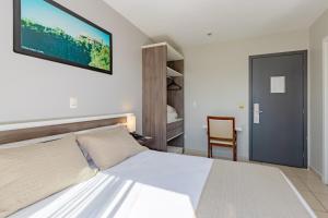 1 dormitorio con 1 cama blanca y 1 silla en Bristol Portal do Iguaçu Curitiba Aeroporto, en Curitiba