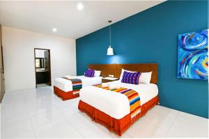 two beds in a room with a blue wall at Hotel Mariachi by Kavia 5th Av in Playa del Carmen