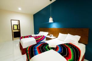 2 camas en una habitación con una pared azul en Hotel Mariachi by Kavia 5th Av en Playa del Carmen