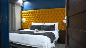 a bedroom with a large bed with a yellow headboard at Qhanolla Guest House in Butha-Buthe