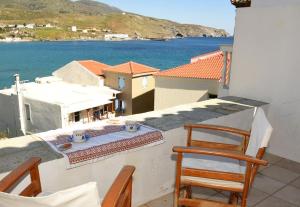 a balcony with two chairs and a view of the water at Panos House Andros in Andros