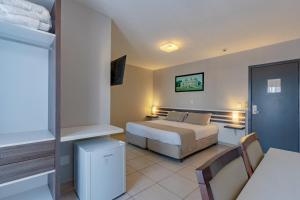 クリチバにあるBristol Portal do Iguaçu Curitiba Aeroportoのベッド、テーブル、椅子が備わるホテルルームです。