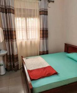 a bedroom with a green bed with a window with curtains at MUSITA GUEST WING MOTEL 