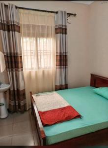 Schlafzimmer mit einem Bett und einem Fenster mit Vorhängen in der Unterkunft MUSITA GUEST WING MOTEL 