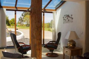 a room with two chairs and a lamp and a window at Ty-Hapus cottage in Jordanston