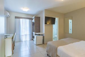 a bedroom with a bed and a desk and a kitchen at Bristol Portal do Iguaçu Curitiba Aeroporto in Curitiba