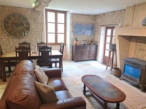 ein Wohnzimmer mit einem Ledersofa und einem Kamin in der Unterkunft Le Moulin Etourneau - 3 gîtes avec 2 piscines in Champagnac