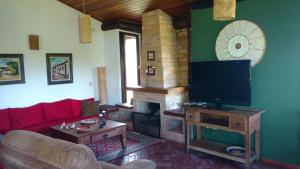 uma sala de estar com televisão e lareira em chale da montanha em Taubaté
