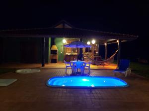 a swimming pool at night with a table and an umbrella at chale da montanha in Taubaté