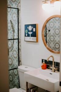 a bathroom with a sink and a mirror and a toilet at Saguaro at Cactus Flower-HOT TUB-Pet Friendly-No Pet Fees! in Albuquerque