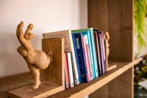 a book shelf with books and a bird statue on it at Appartement midden op het eiland: Pension-Nada in Willemstad