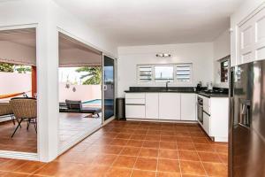 a kitchen with white cabinets and a tile floor at Appartement midden op het eiland: Pension-Nada in Willemstad