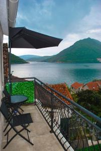 a balcony with a table and an umbrella and a lake at Apartment Mediterraneo Blue Sky in Perast