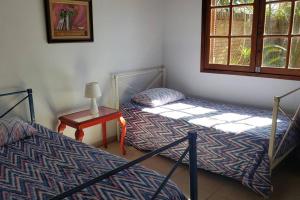 two beds in a room with a table and a window at Casa ampla no Laranjal in Pelotas
