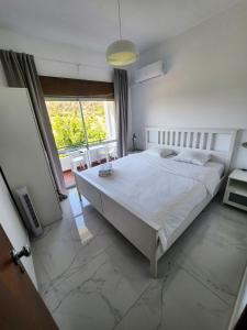 um quarto com uma cama branca e uma grande janela em AAA Ana Albufeira Apartments em Albufeira