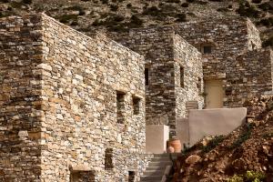 Apsila Pool Suites في Sifnos: مبنى حجري مع درج يؤدي للباب