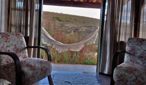 2 sillas frente a una ventana con vistas en Pousada Serra da Paz en Carrancas