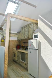 a kitchen with a white refrigerator and wooden cabinets at Apartment Mediterraneo Blue Sky in Perast