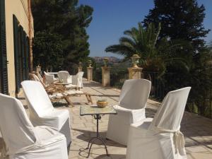 a row of white chairs and tables on a patio at Tenuta Bartoli Maison de Charme in Mazzarino