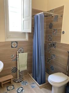 a bathroom with a toilet and a blue shower curtain at Casa Dalfea in Mazara del Vallo
