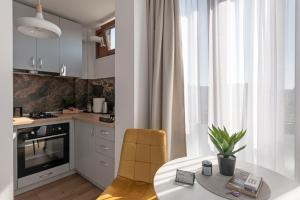 een keuken met een witte tafel en stoelen en een tafel en een raam bij Moon Apartments in Cluj-Napoca