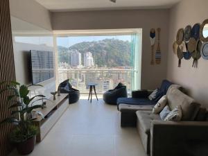 un soggiorno con un divano e una grande finestra di Book Santos - Unlimited 2112 - Moderno e Elegante a Santos